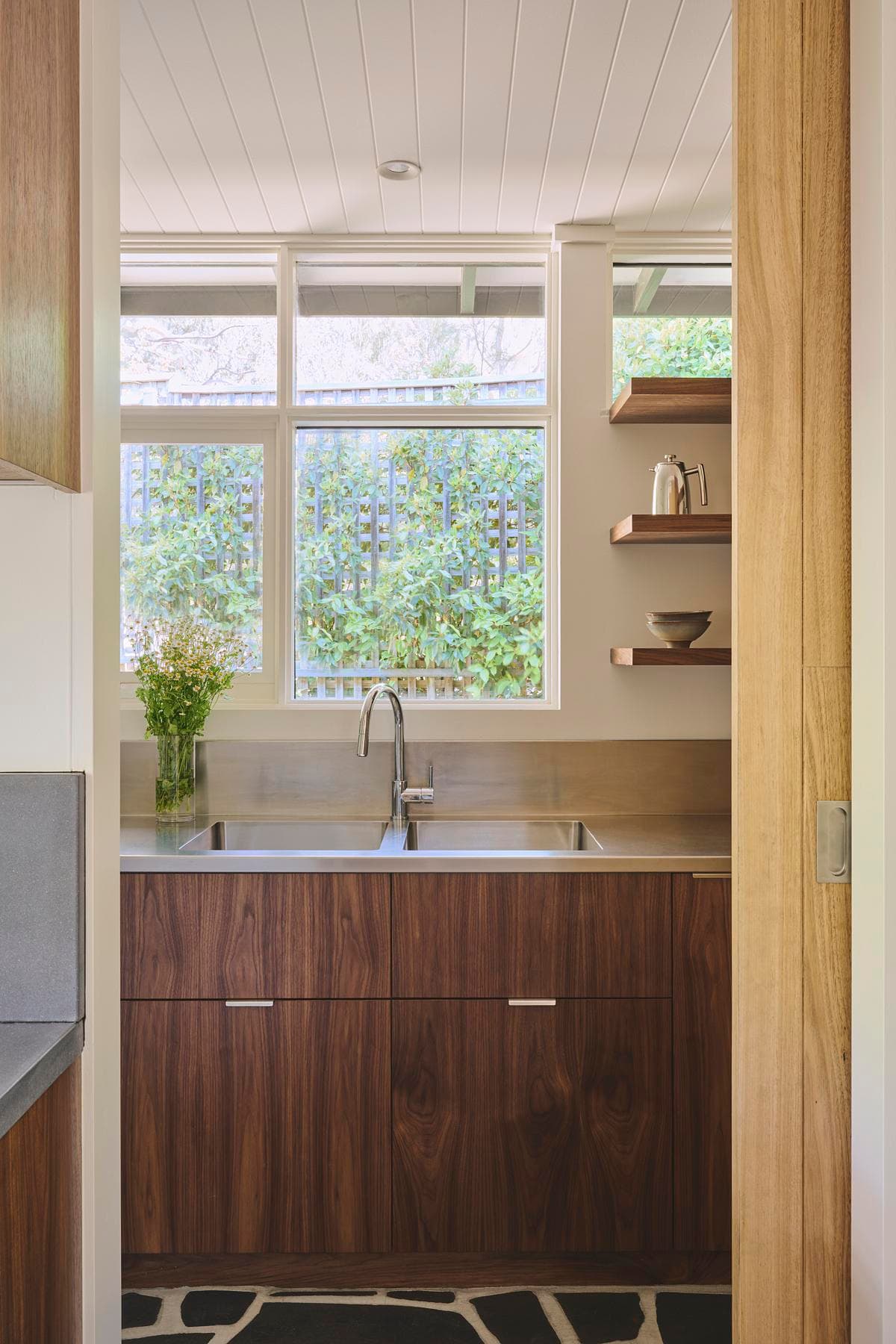 Kitchen sink beneath a window overlooking greenery