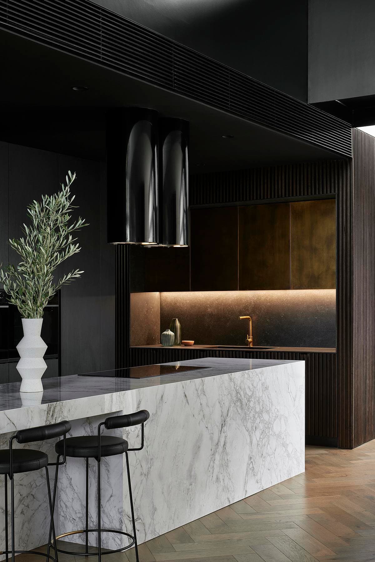 A pale island contrasts with the kitchen's dark cabinetry and concealed lighting.