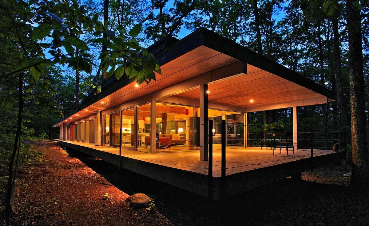 A projecting timber-lined roof shelters the glazed corner and deck.