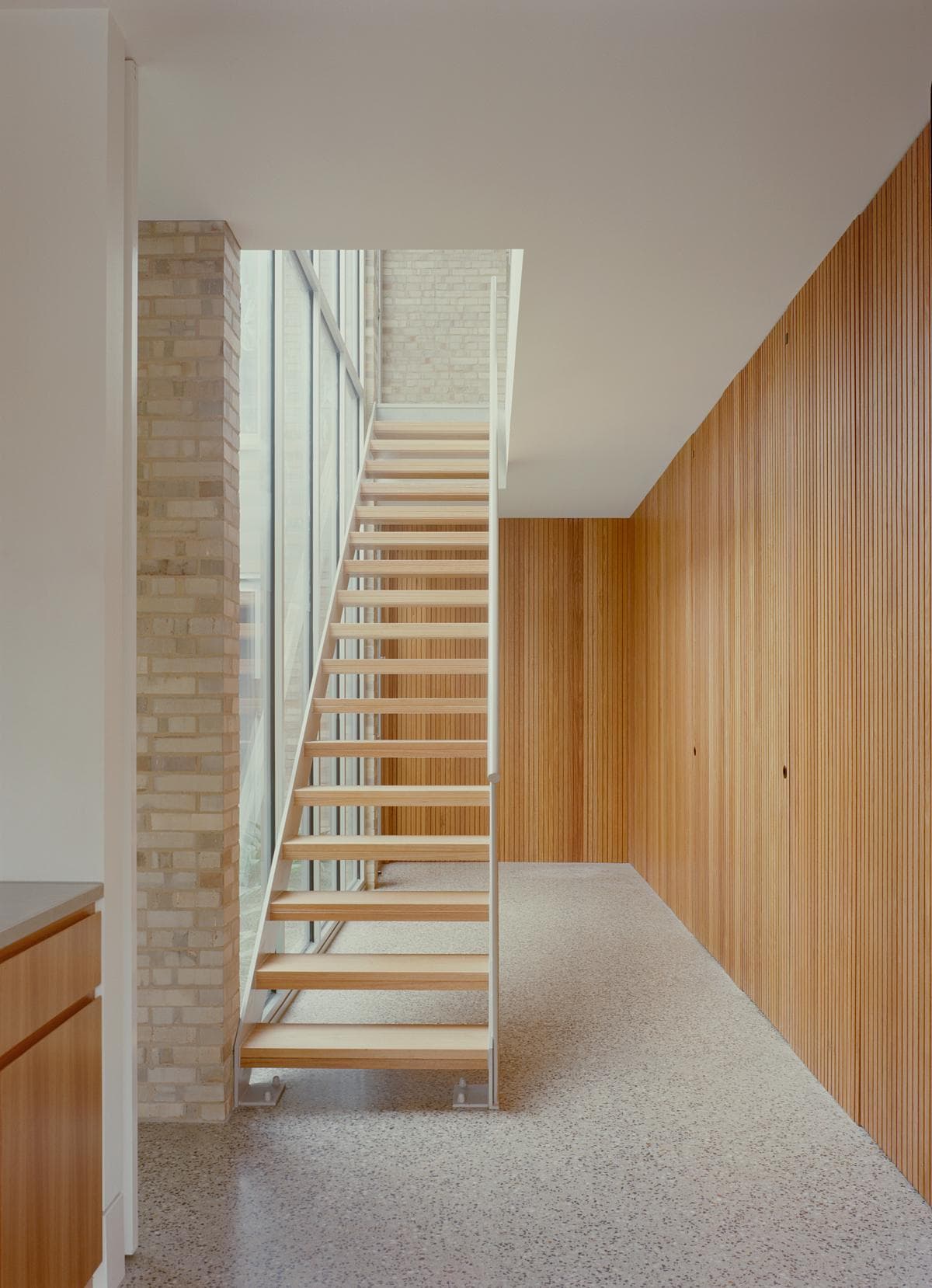 The stair links the timber-lined hall with the living spaces above.