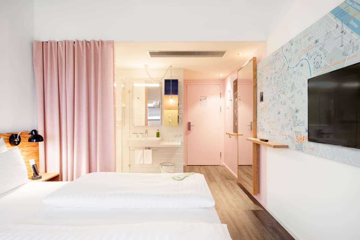 A guest room brings a bed, washbasin and bathroom area into a compact plan.