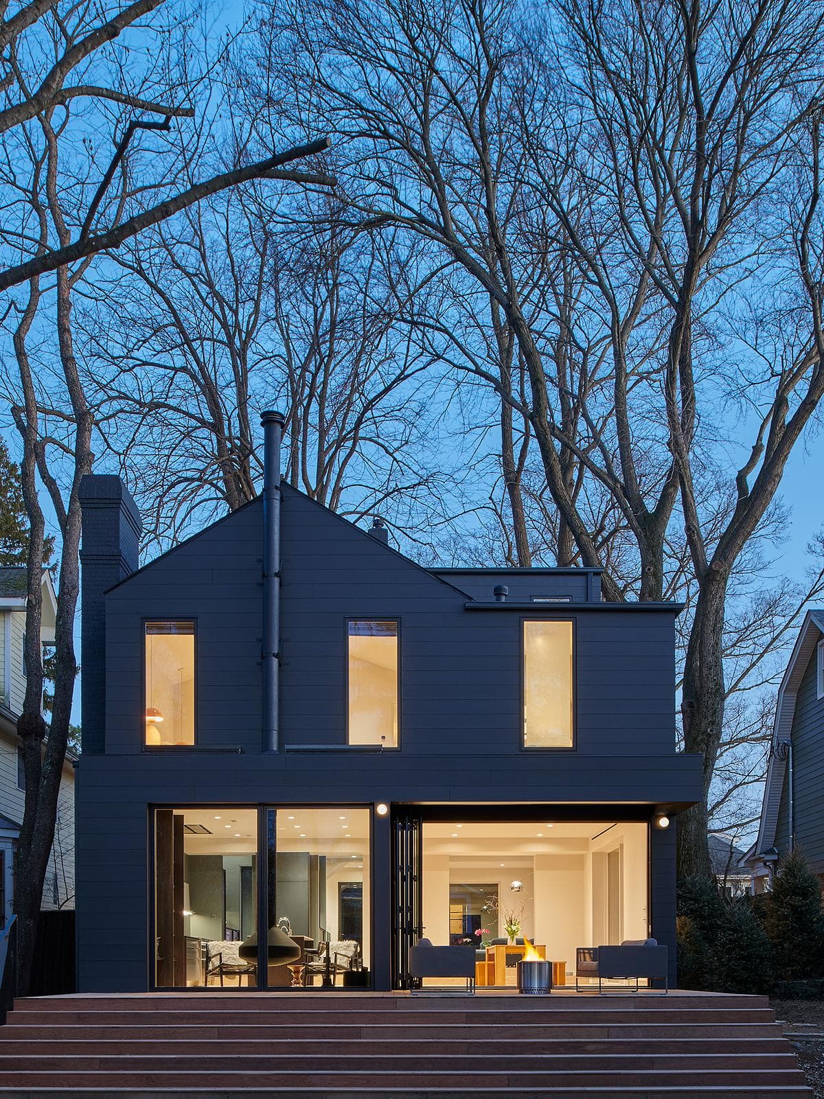 The dark-clad rear elevation and timber deck at dusk.