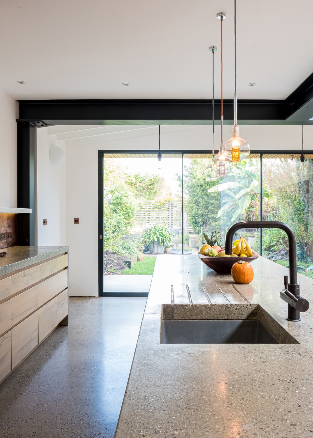 The concrete kitchen island faces the glazed opening to the garden.