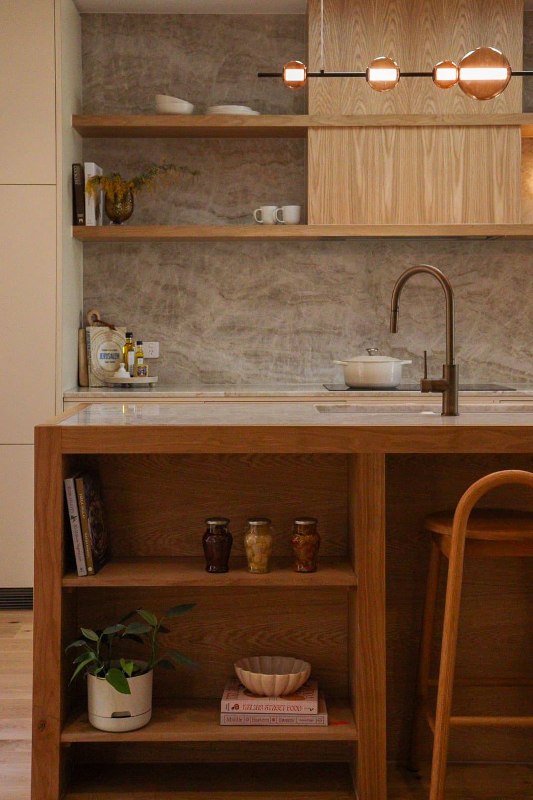 Timber cabinetry and a stone splashback frame the kitchen.