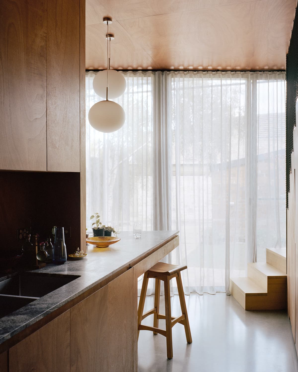 A projecting kitchen bench forms a breakfast bar beside the glazed courtyard.