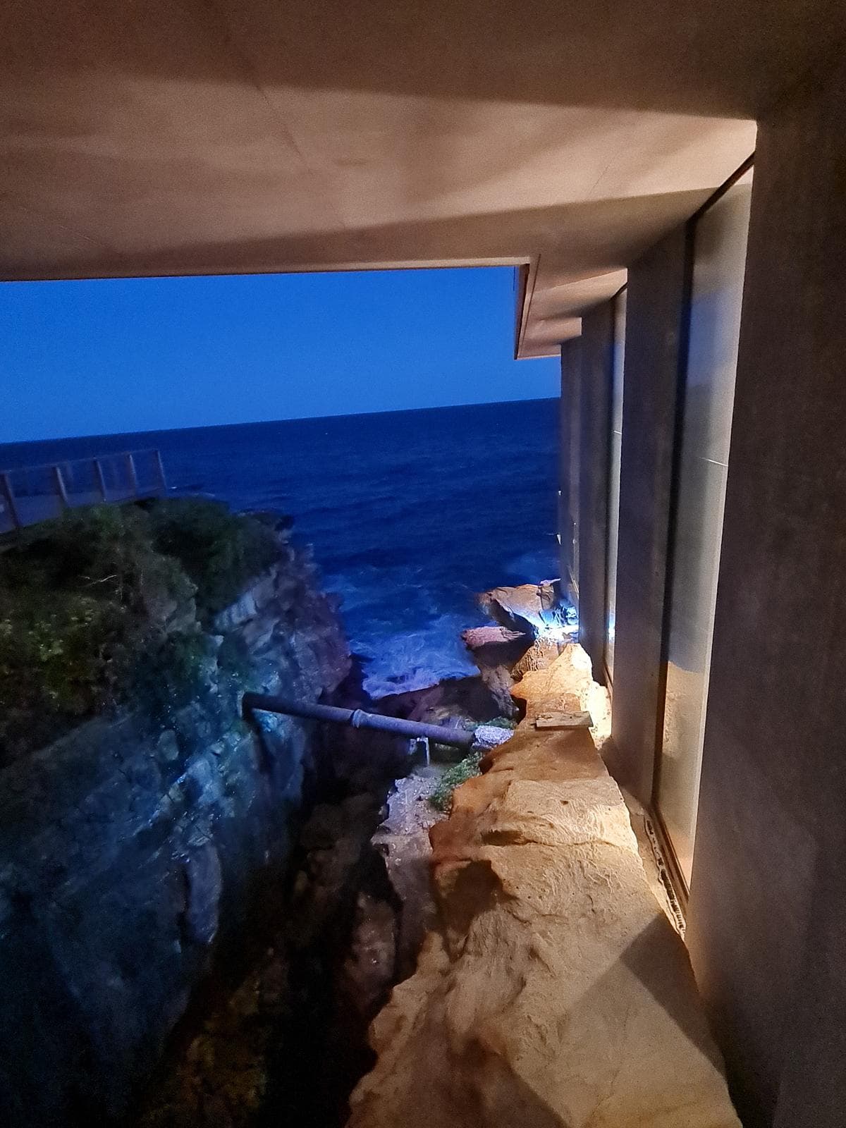 A low opening frames the rocky ravine and ocean at dusk.