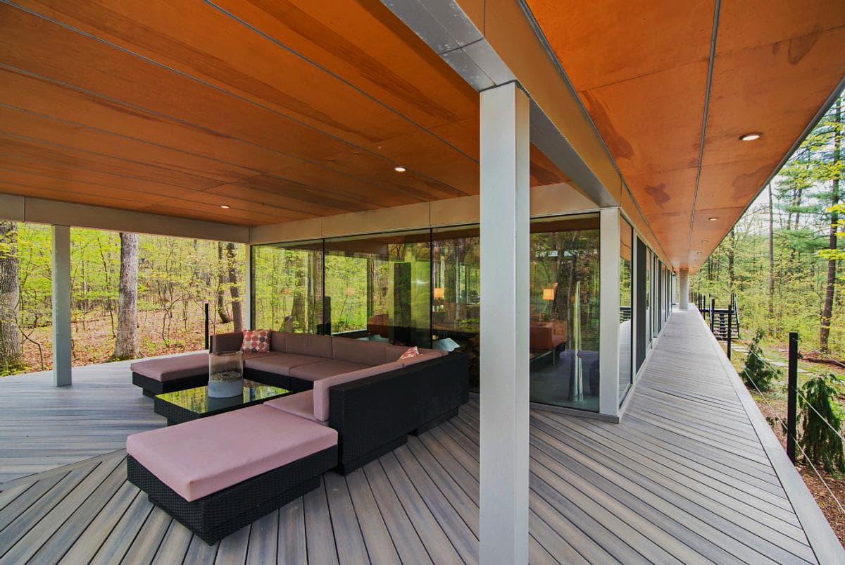 A covered deck runs along the glazed wall of the house.