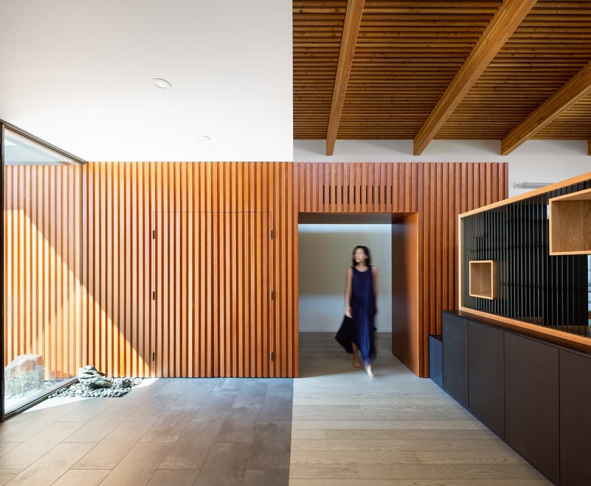 Timber screens and ceiling boards define the tall arrival space.