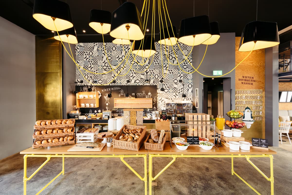The shared breakfast area combines a café counter, patterned wall and suspended lighting.
