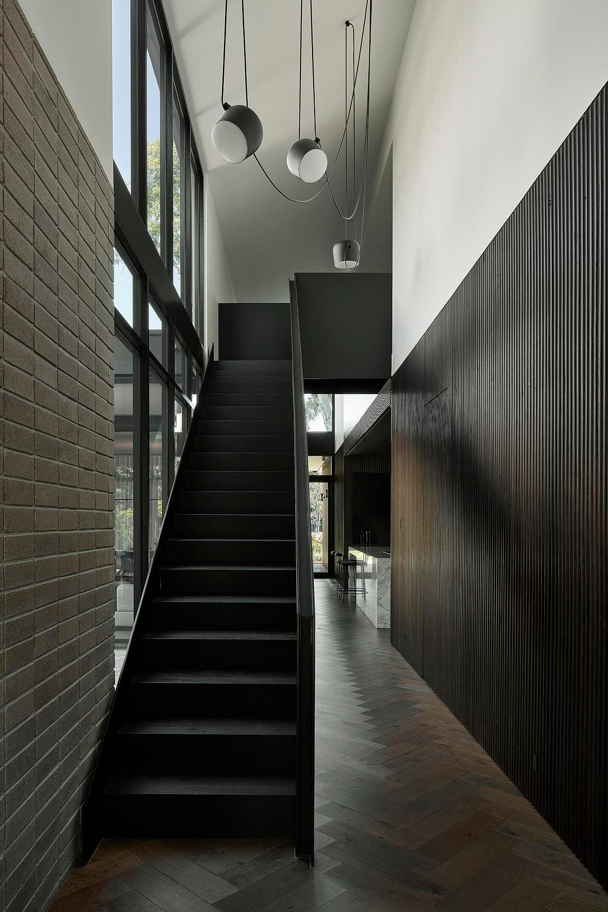 The folded steel staircase rises beside a fluted timber wall.