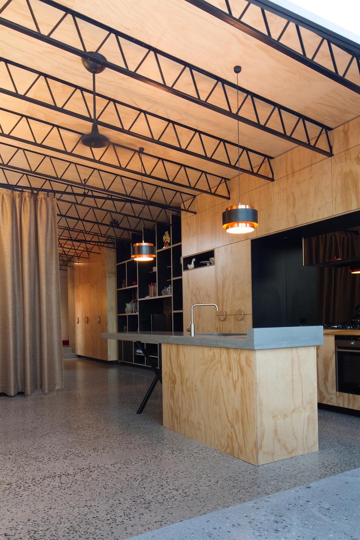 The kitchen island sits beneath the exposed roof structure.