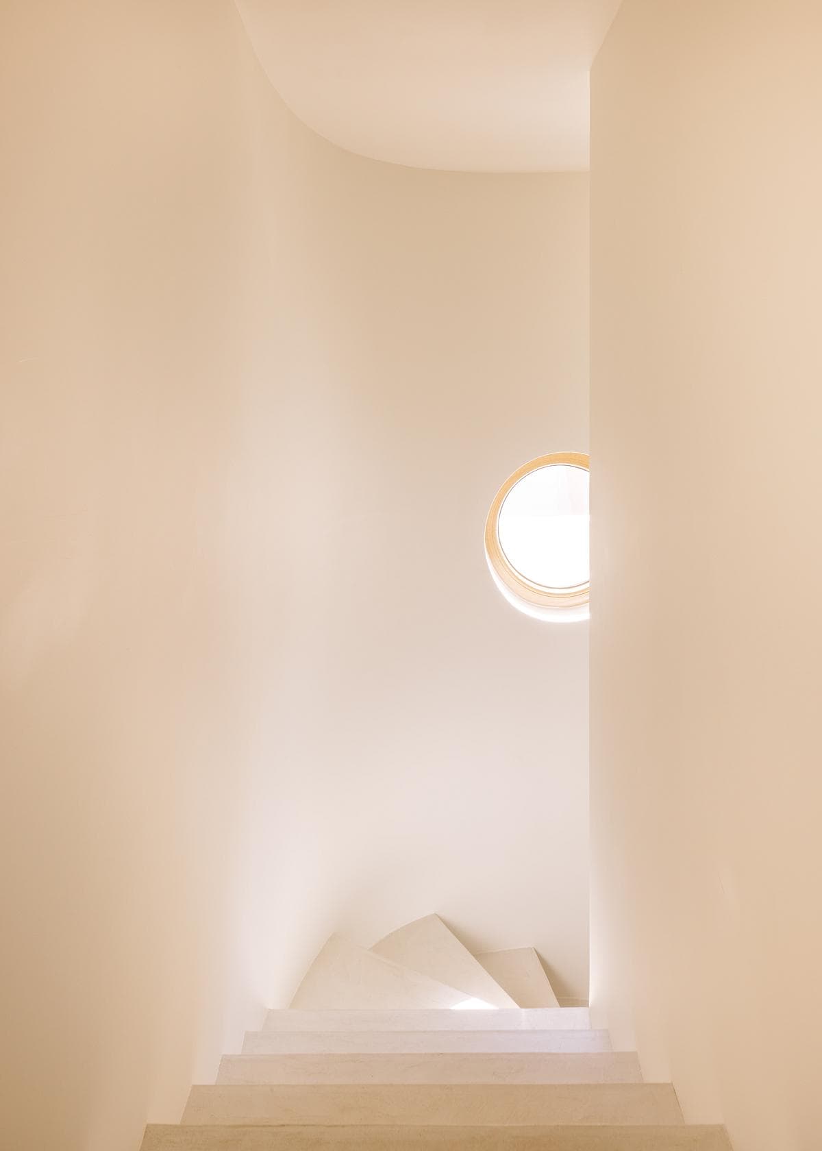 A circular window lights the curved stair.