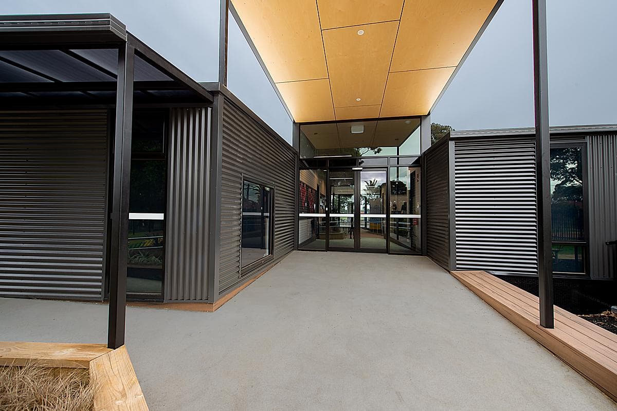 Covered entrance between the corrugated-clad learning wings.
