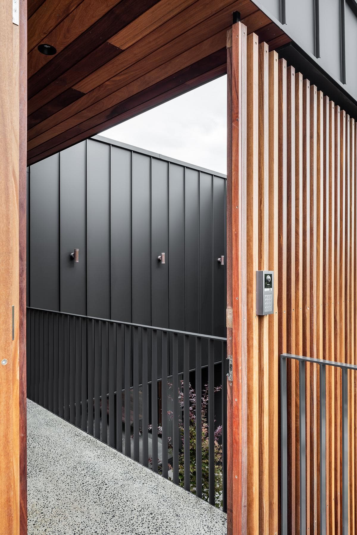 Dark cladding meets timber screening beside the entrance.