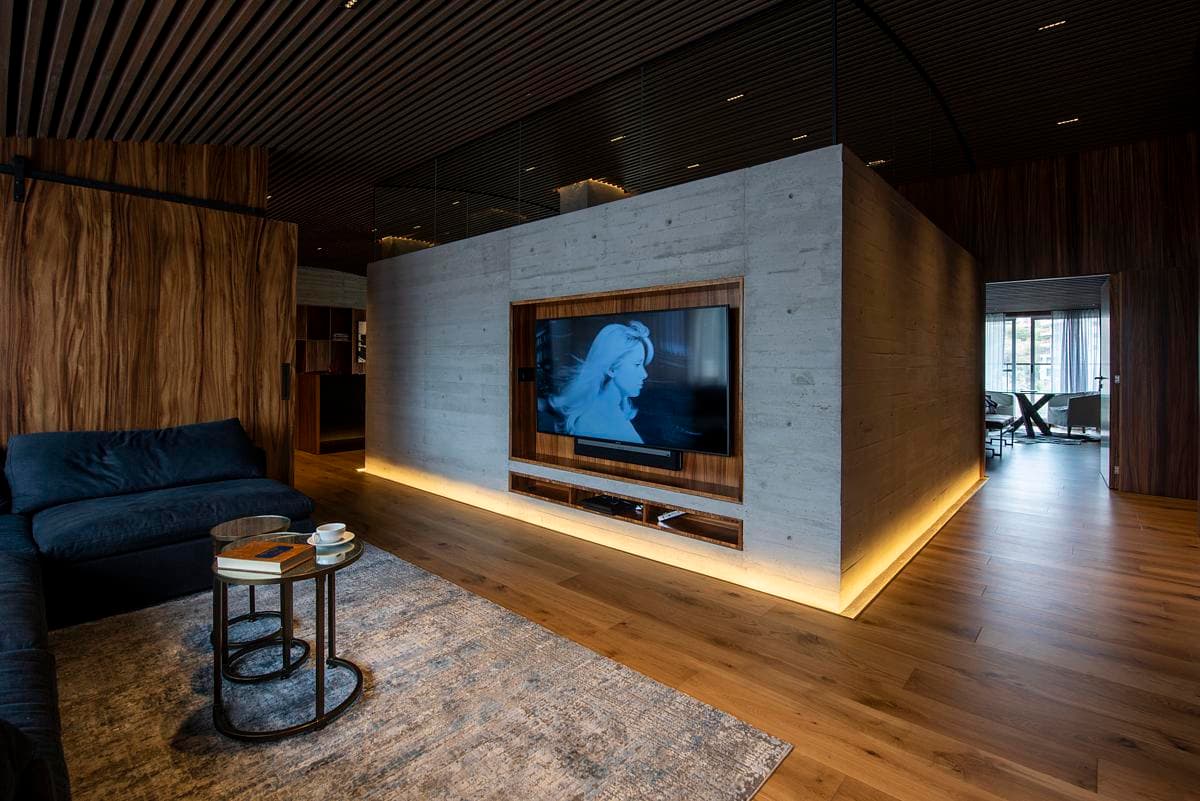 A concrete wall and concealed lighting define the television area.