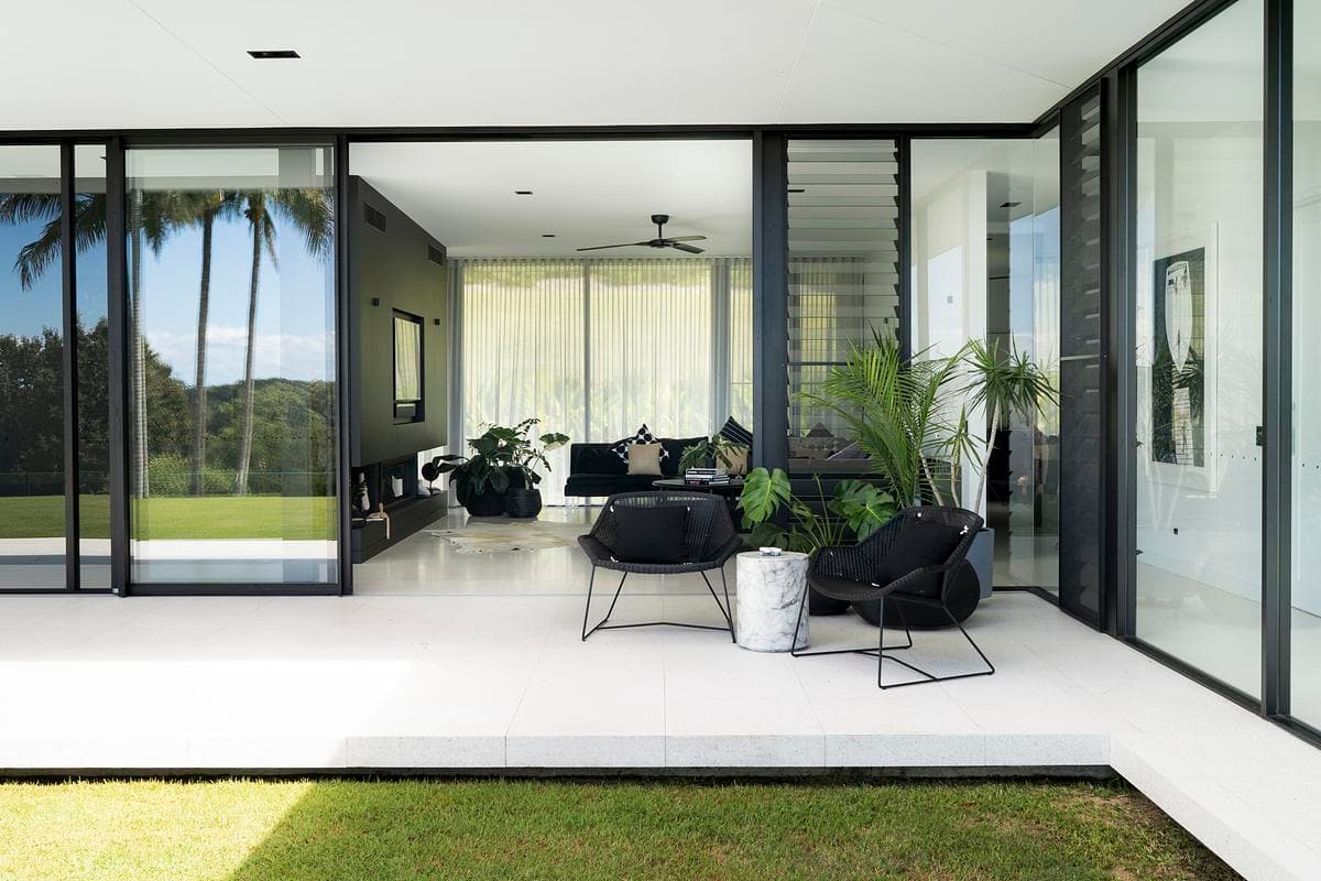 Living room opening to the lawn through full-height sliding glazing.