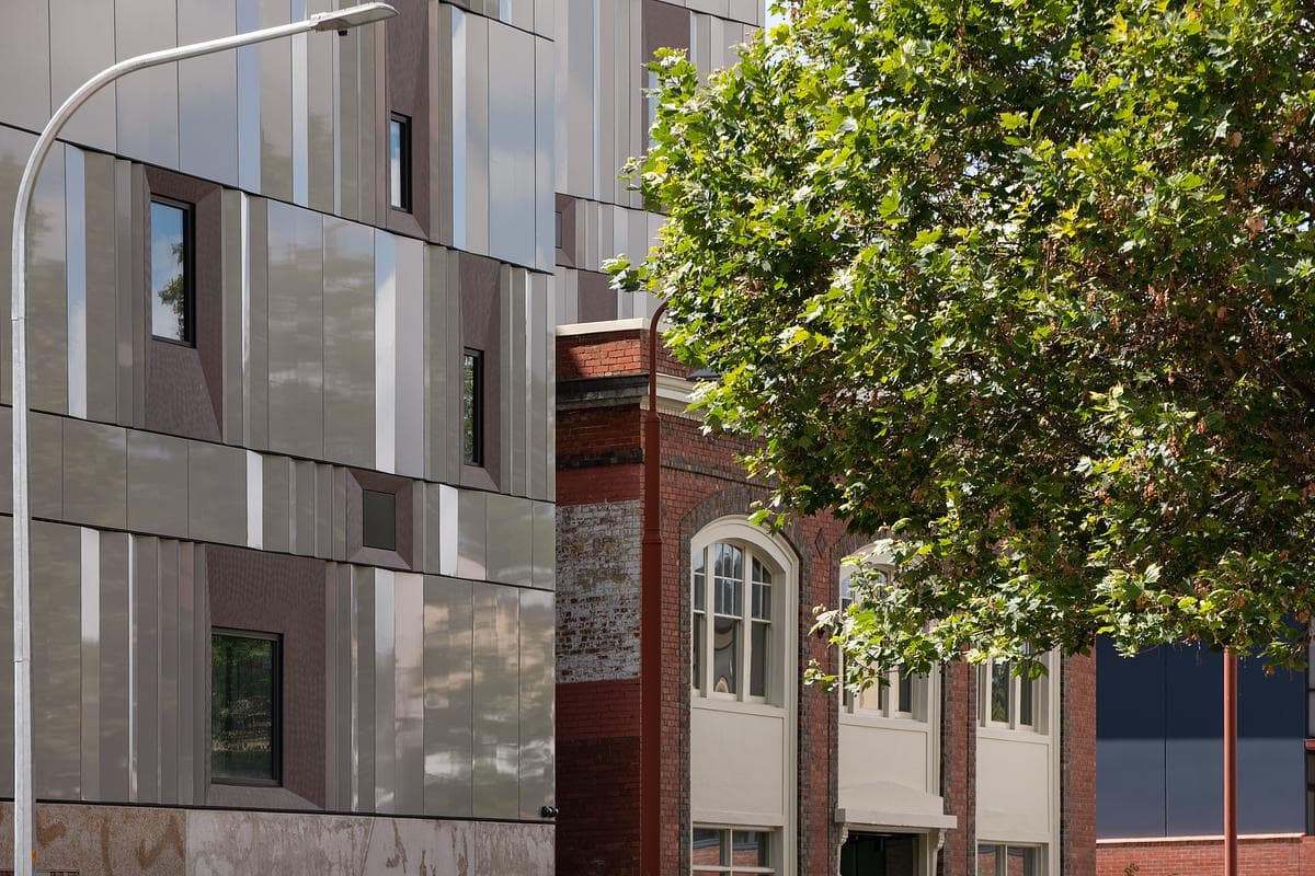 Folded metal panels sit beside the smaller scale of the historic buildings.