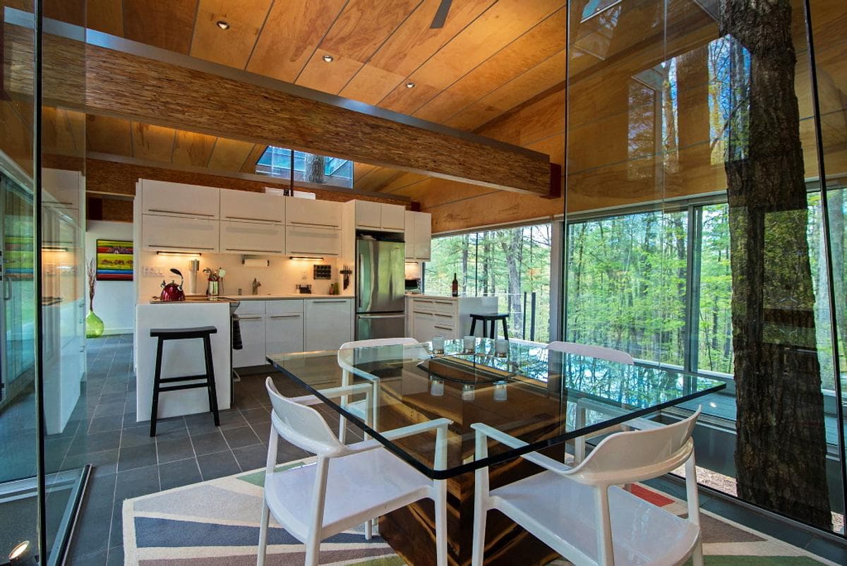 Timber beams span the kitchen and dining area beside the trees.