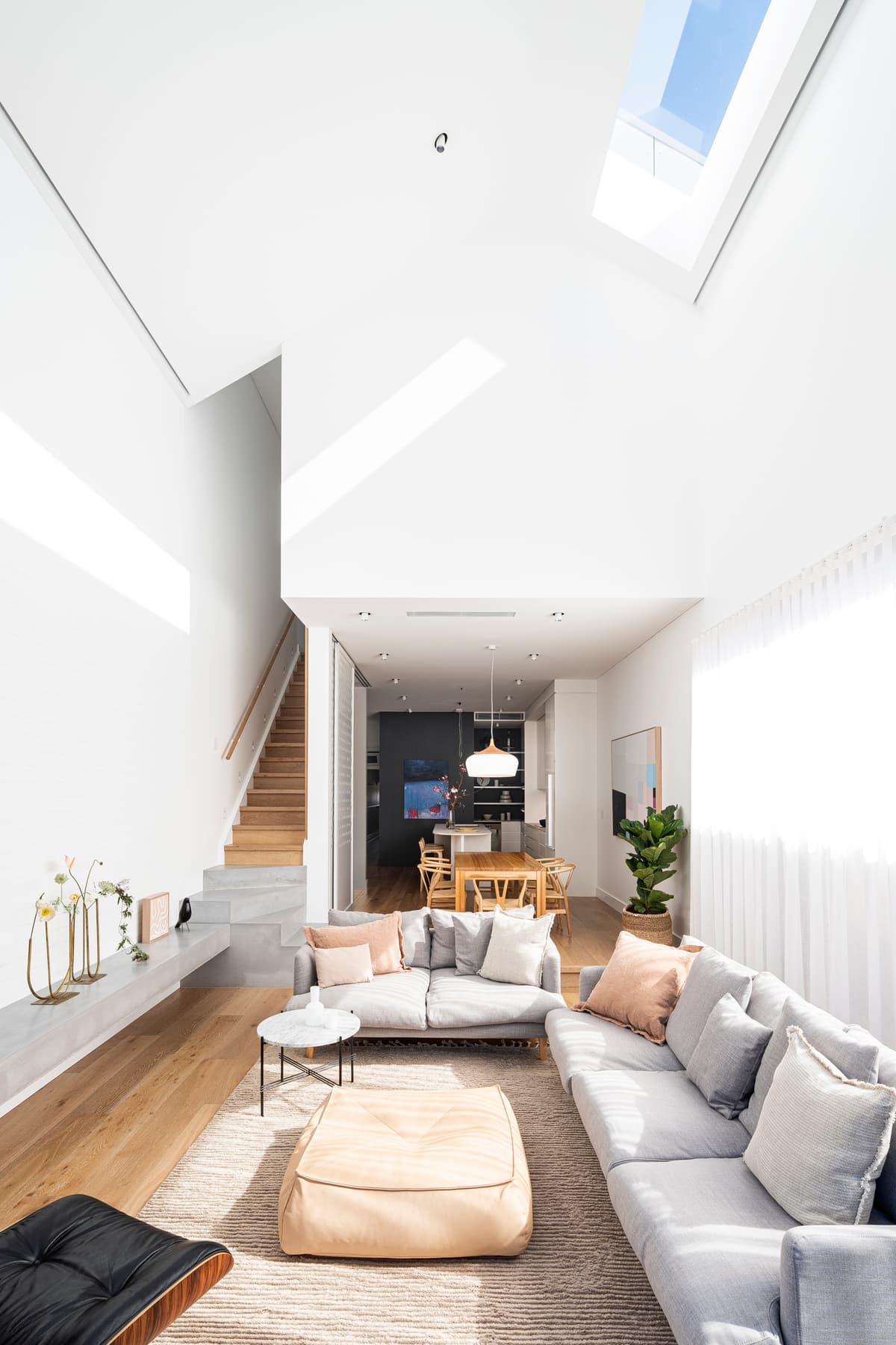 Roof glazing and a double-height ceiling bring daylight deep into the living room.
