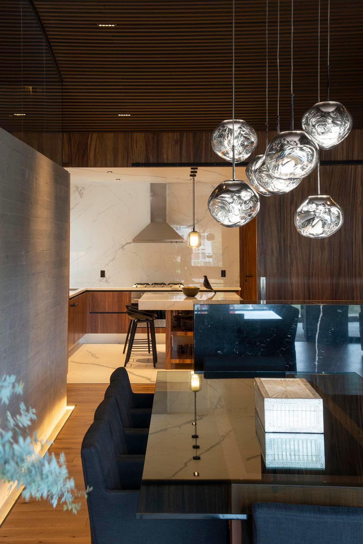 Pendant lights hang above the dining table beside the kitchen.