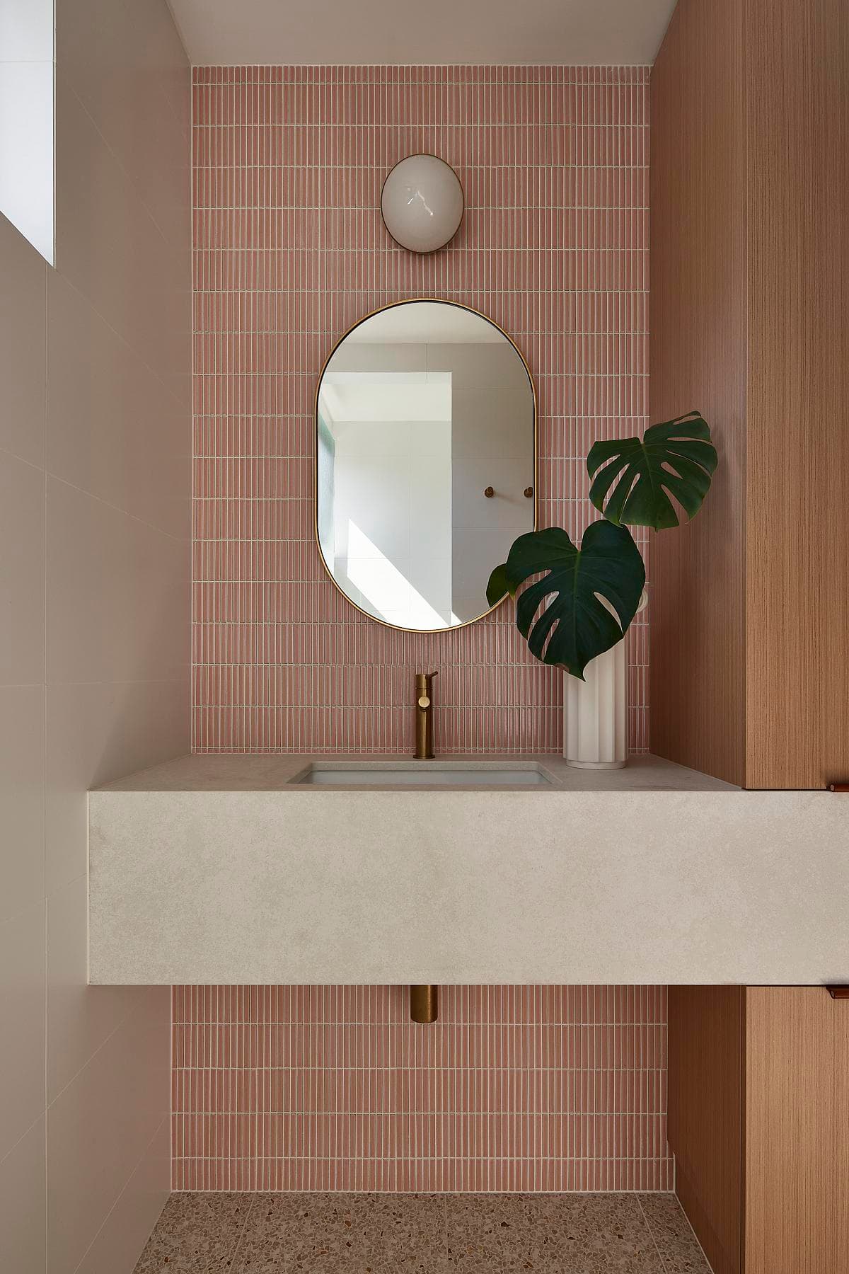 Pink tiles and a pale vanity soften the upstairs bathroom.