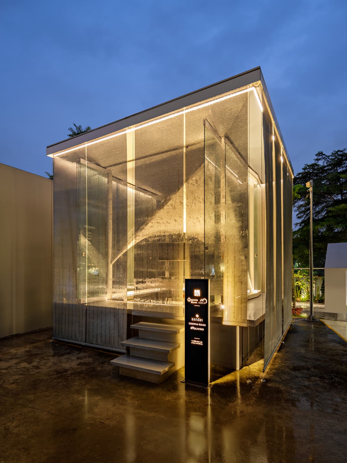 Light picks out the enclosure and the woven surface after dark.