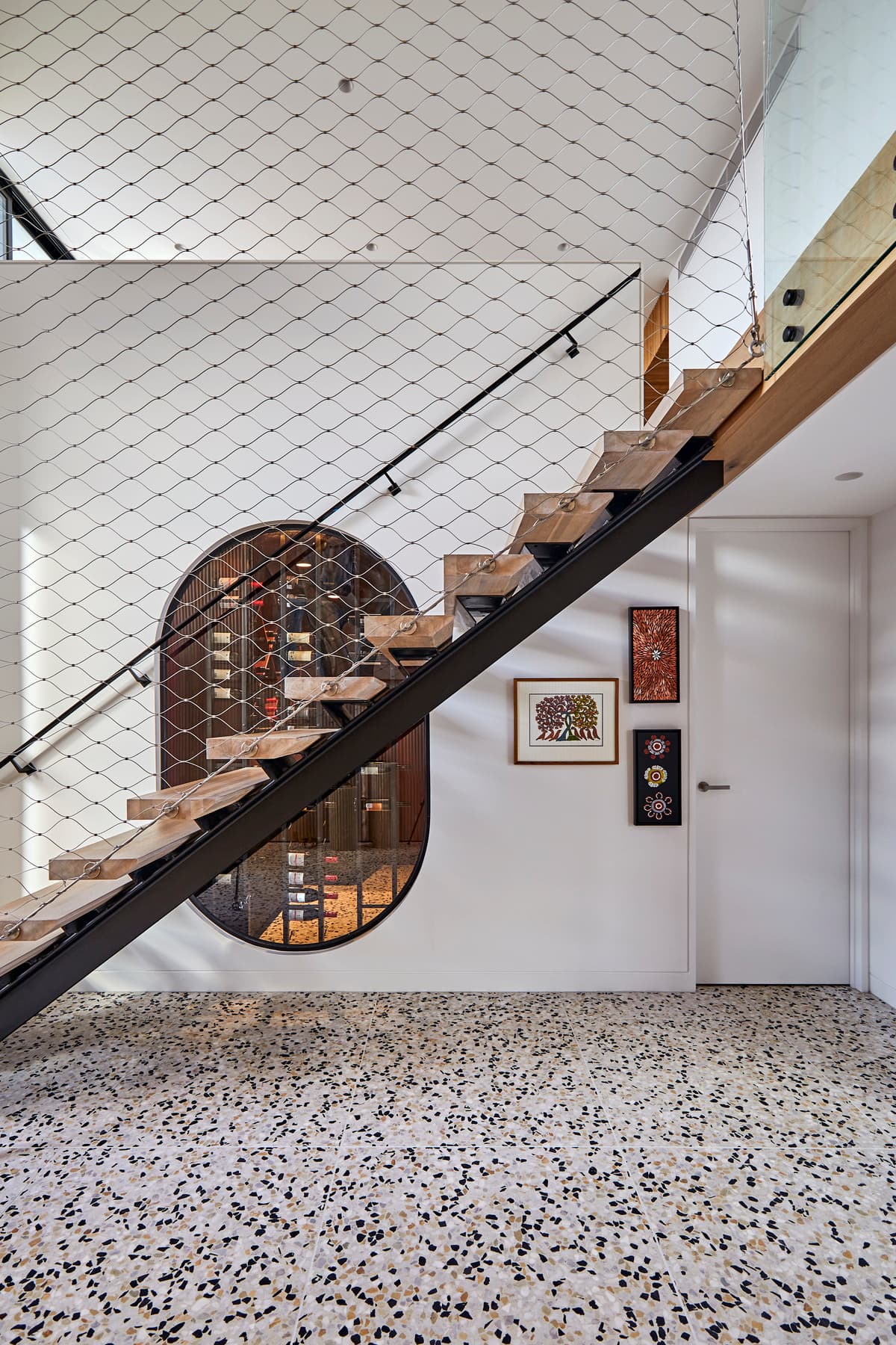 An open timber stair rises above the terrazzo floor.