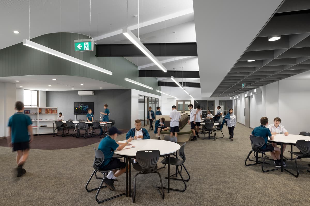 Students work at round tables in an open learning area.