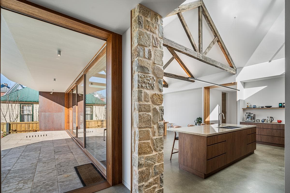 Sliding timber doors connect the stone-lined living space with the garden.