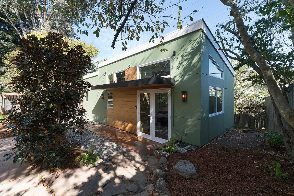 The garden home combines a sloping roof, high-level glazing and green wall finishes.