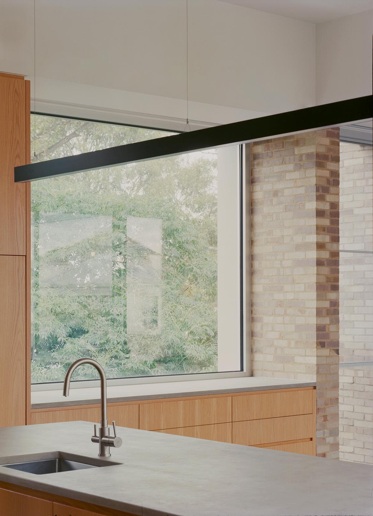 A wide mirror and window bring light into the bathroom.