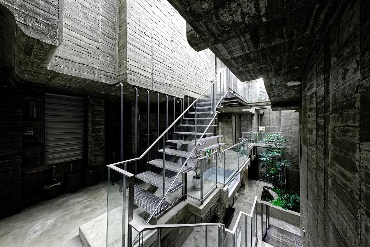 Steel stairs and walkways crossing the planted concrete courtyard.