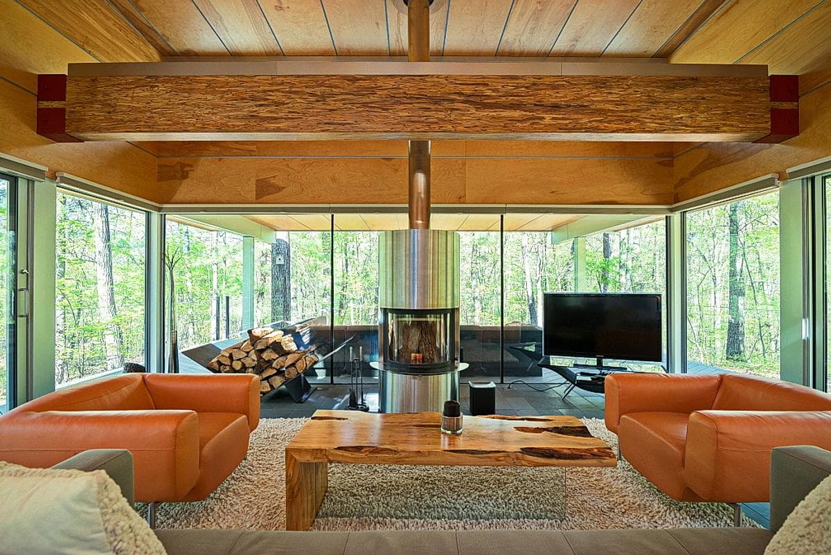 The fireplace anchors a sitting area enclosed by woodland views.