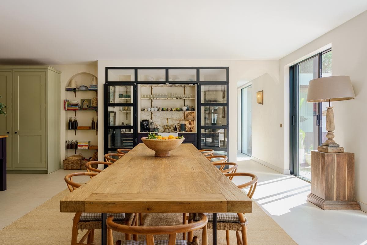 Timber dining table between the kitchen and glazed living-room partition