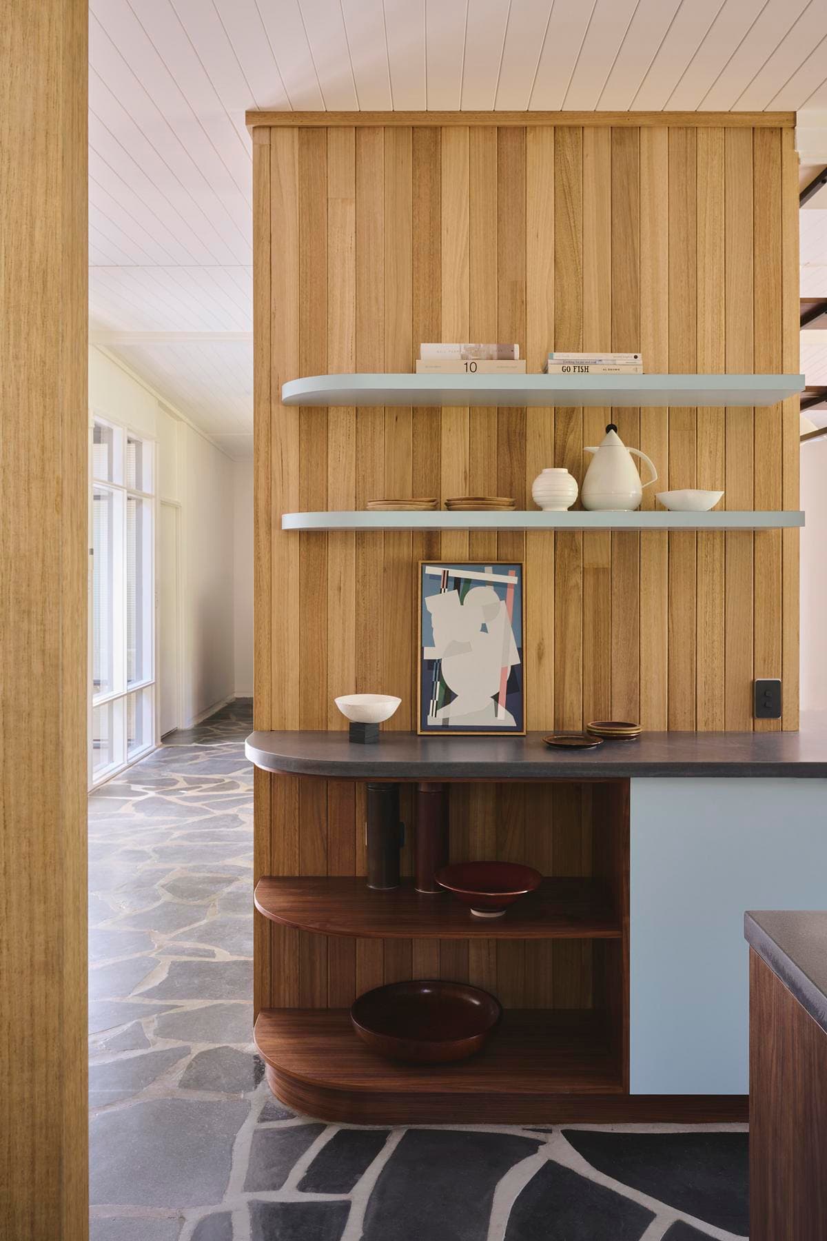 Curved joinery and open shelves connecting kitchen and dining spaces