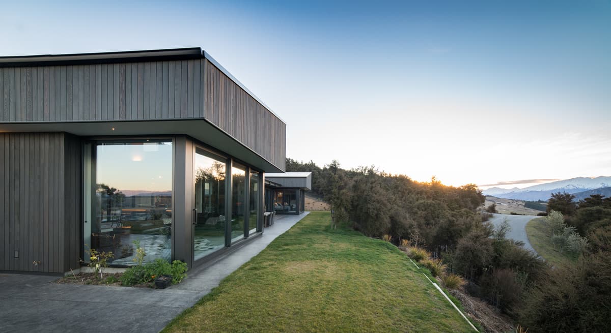 Kanuka Rise: cedar-clad volumes beside the garden at dusk