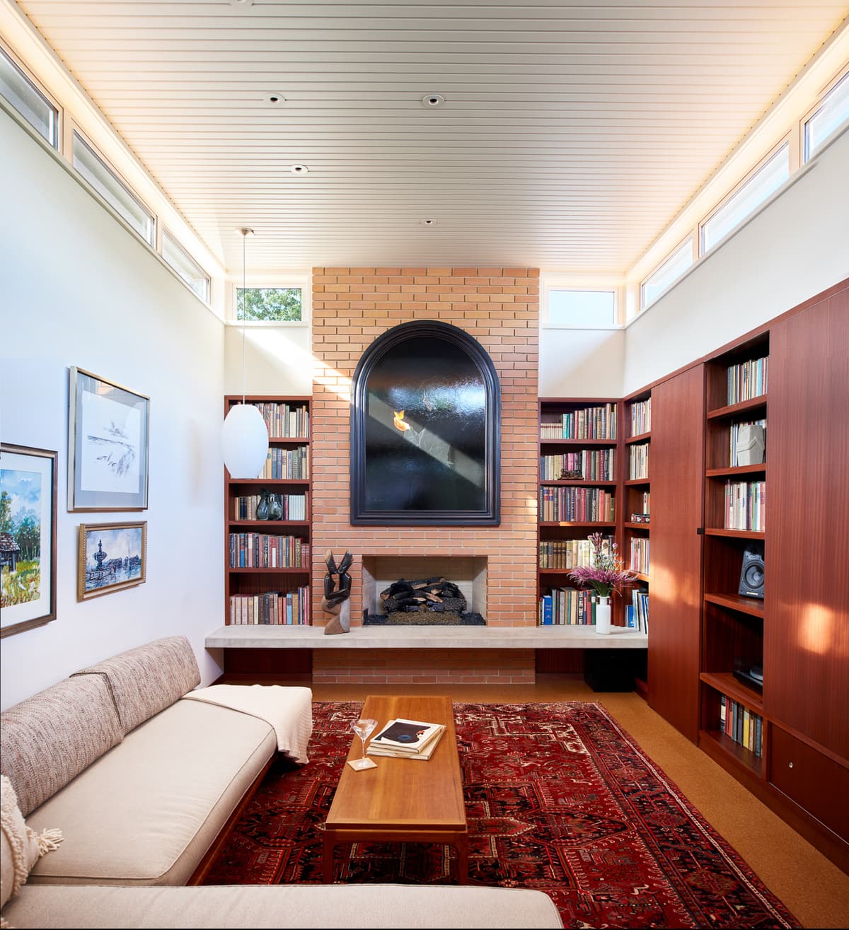 A tall living space combines restored brickwork, bookshelves and timber surfaces.
