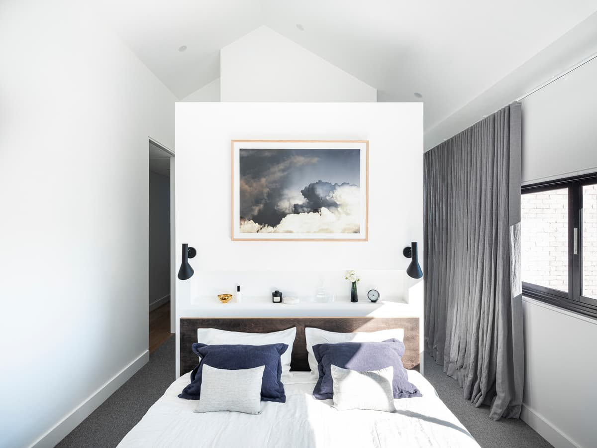 Fitted joinery forms the bedroom headboard, with a glazed ensuite behind.