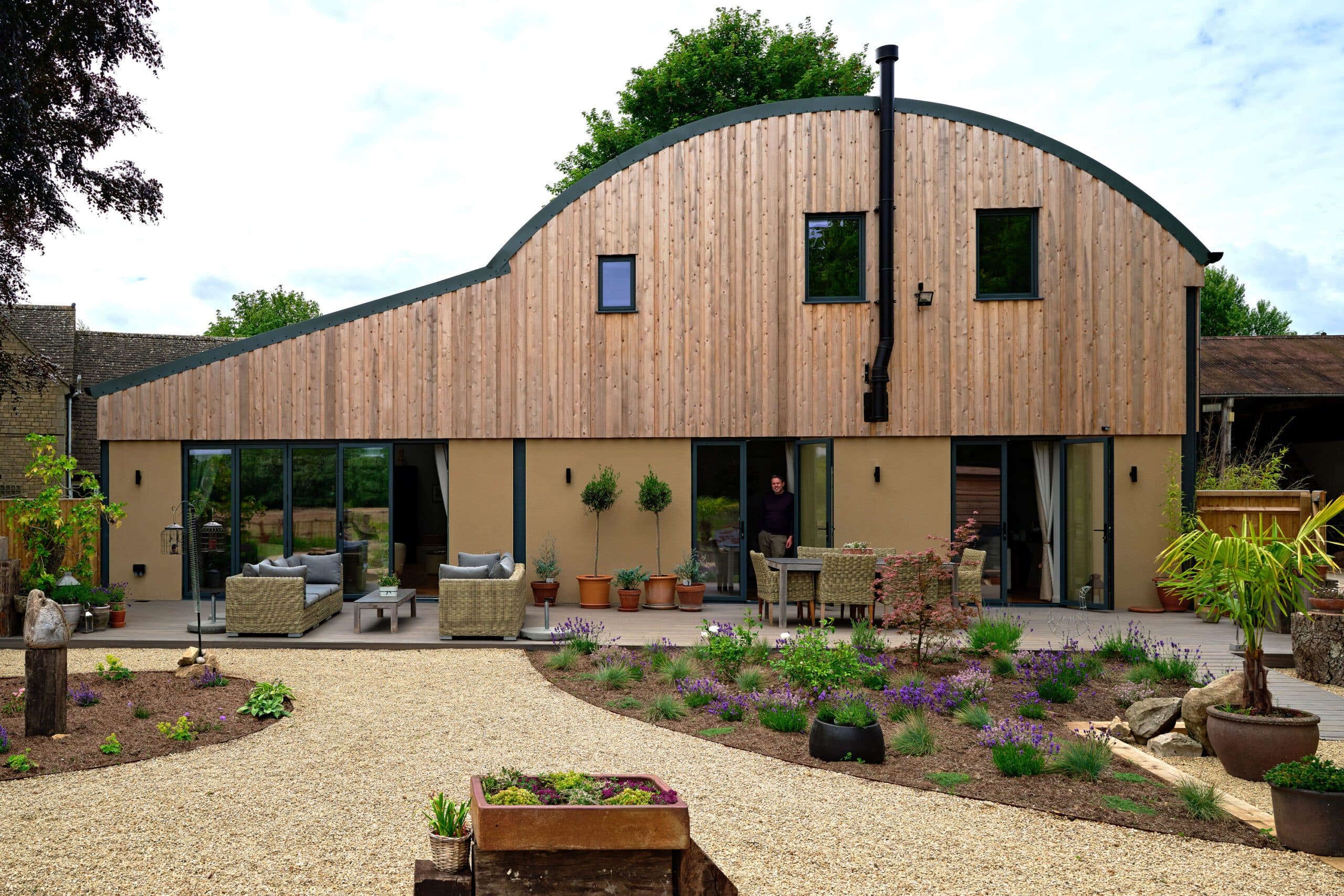 Long elevation of the barn conversion with full-height glazing opening onto a planted garden