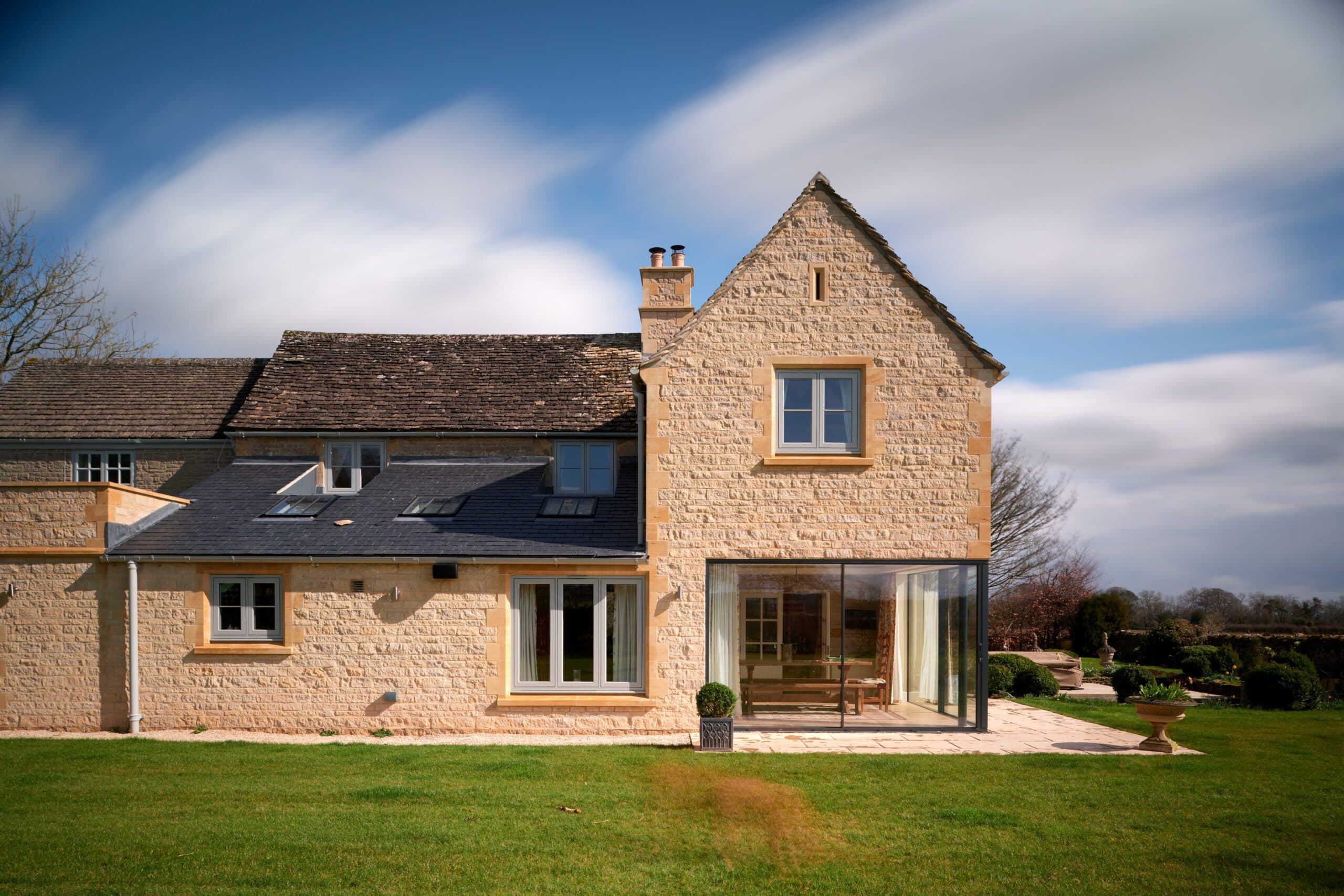 Rear elevation of the stone house with a frameless glazed garden room