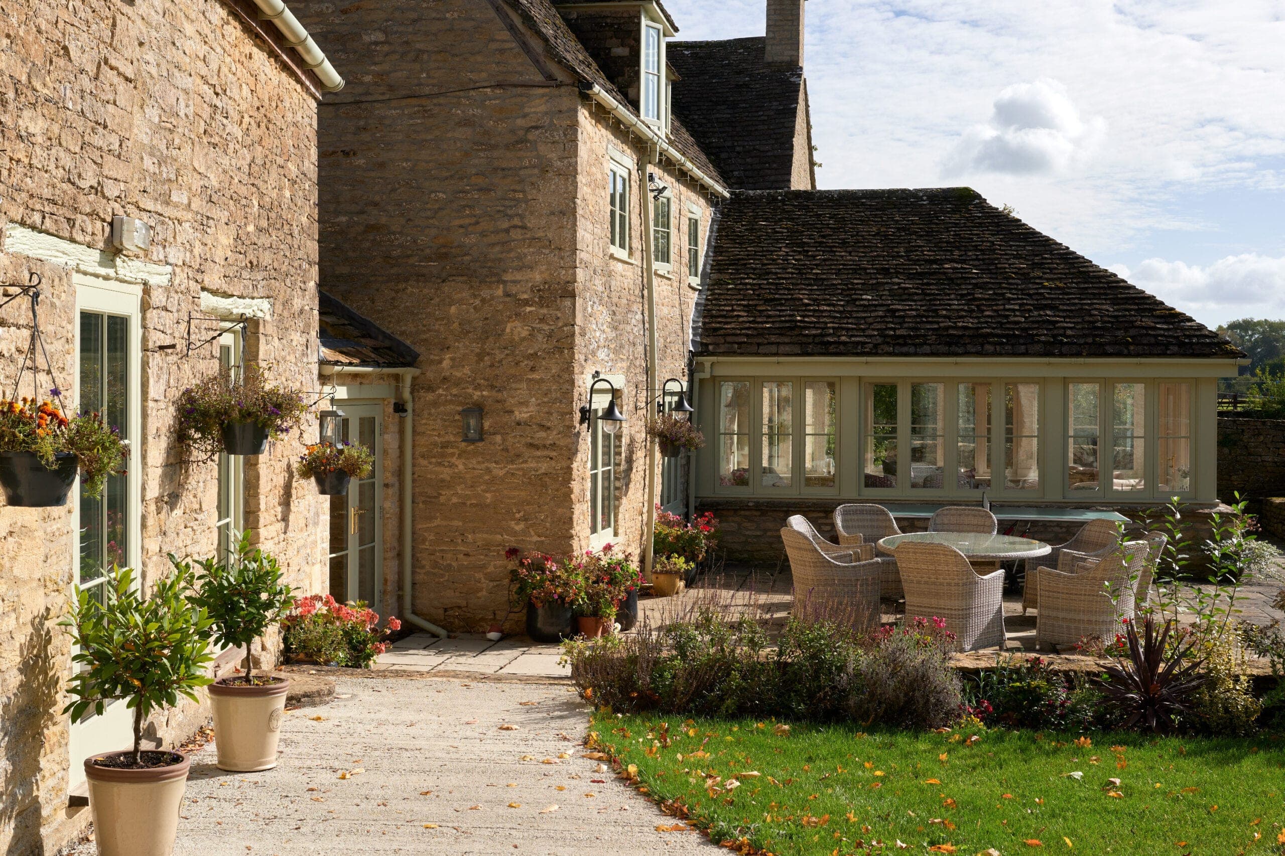 Stone courtyard terrace with outdoor seating beside a glazed garden room