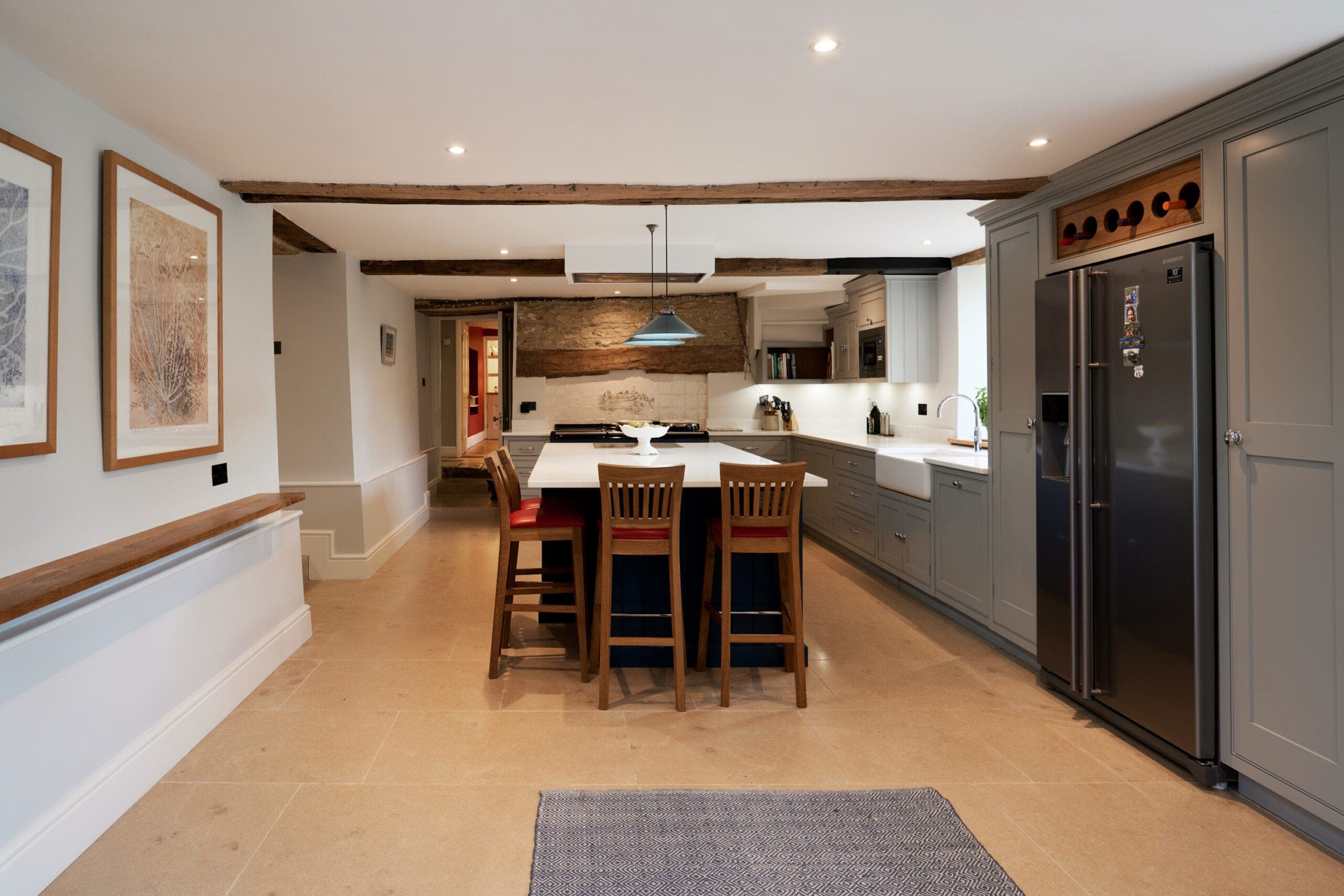Long kitchen with exposed timber beams, a central island and a stone floor