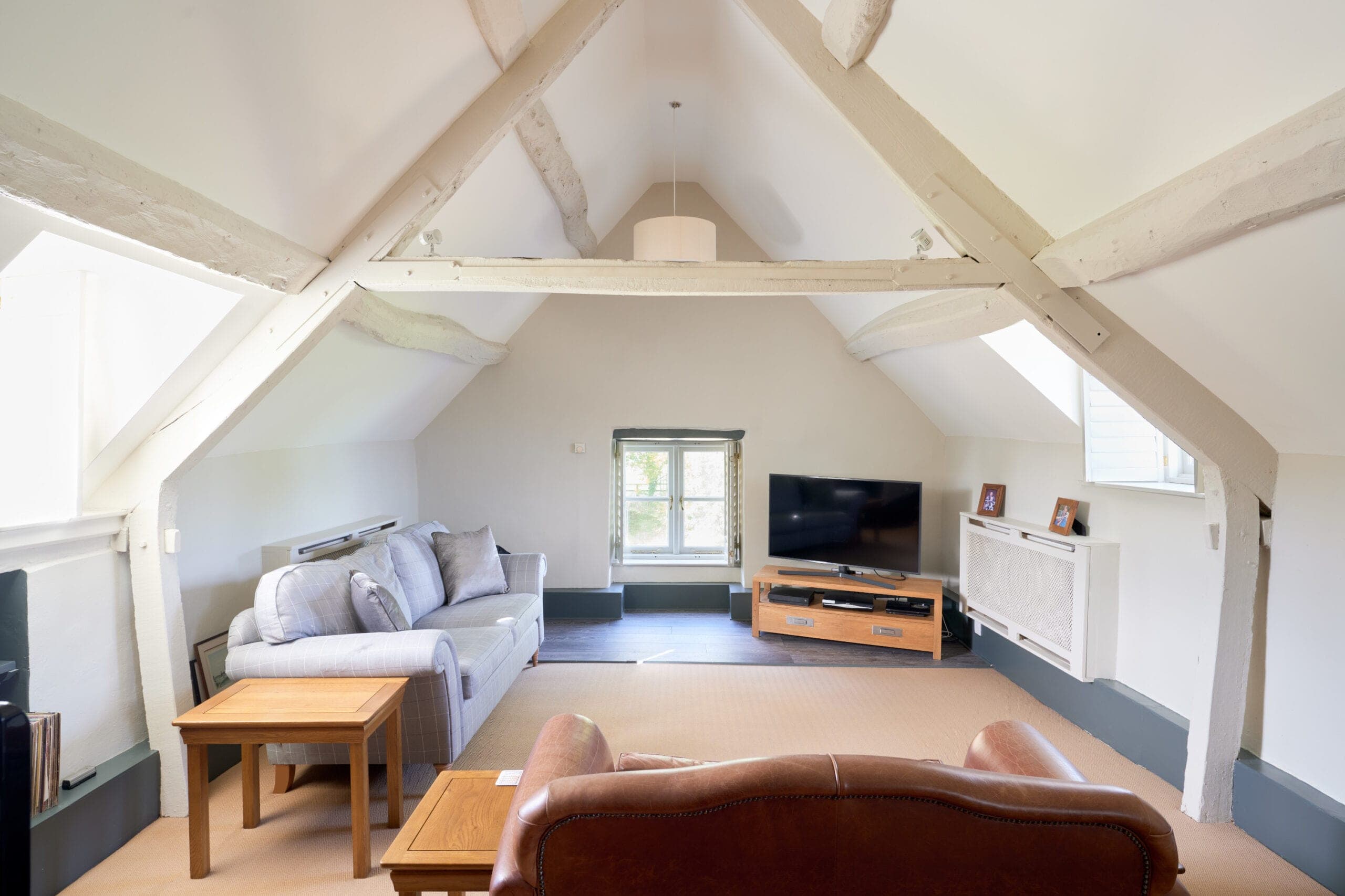 Sitting room in the roof space with whitewashed timber trusses