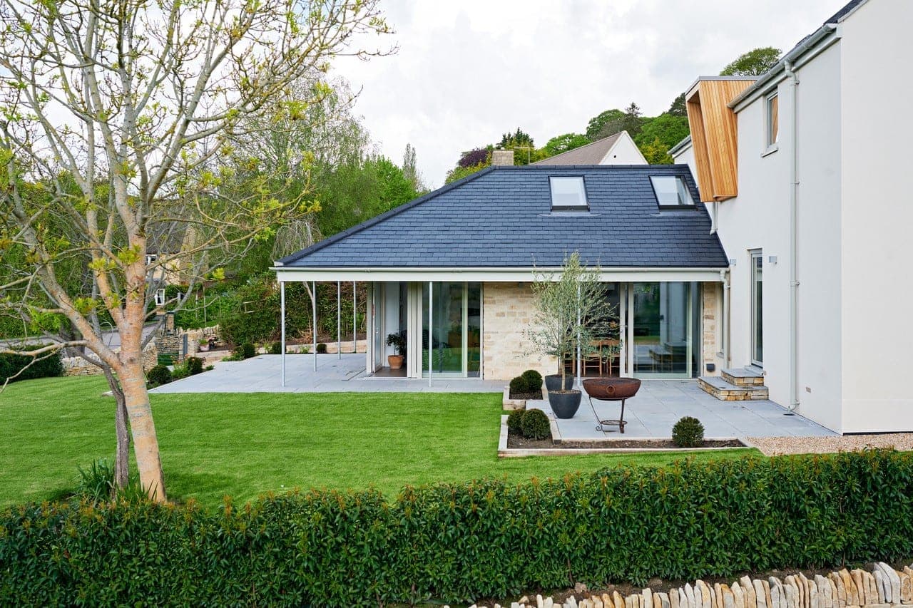 Single-storey slate-roofed wing with glazed doors opening onto a stone terrace