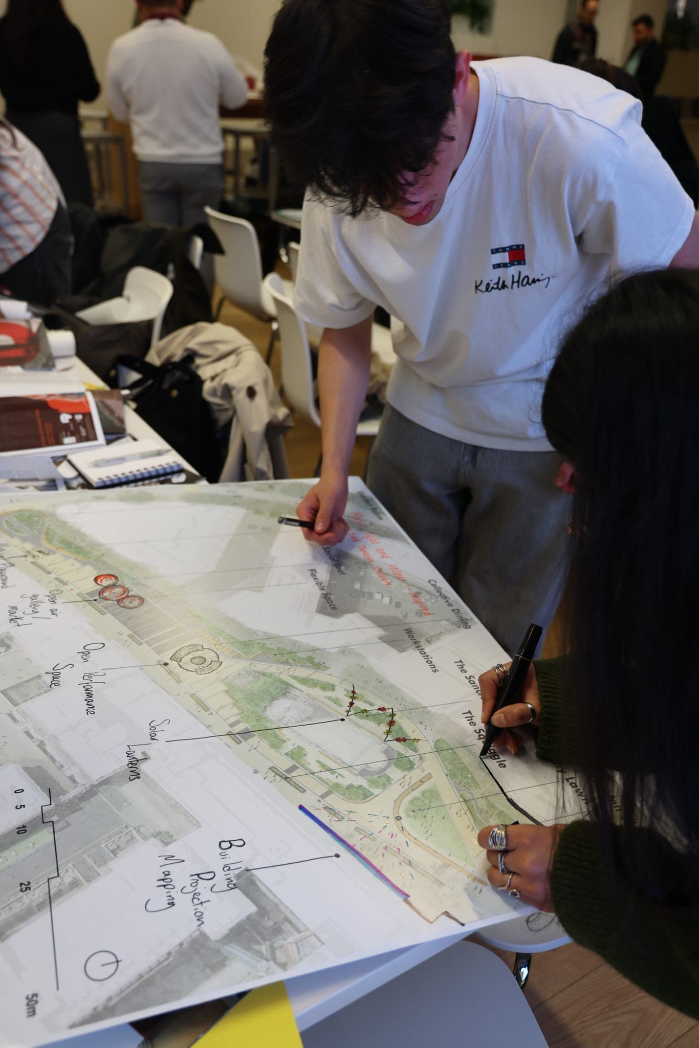 Two participants marking a large hand-drawn map spread across a table.