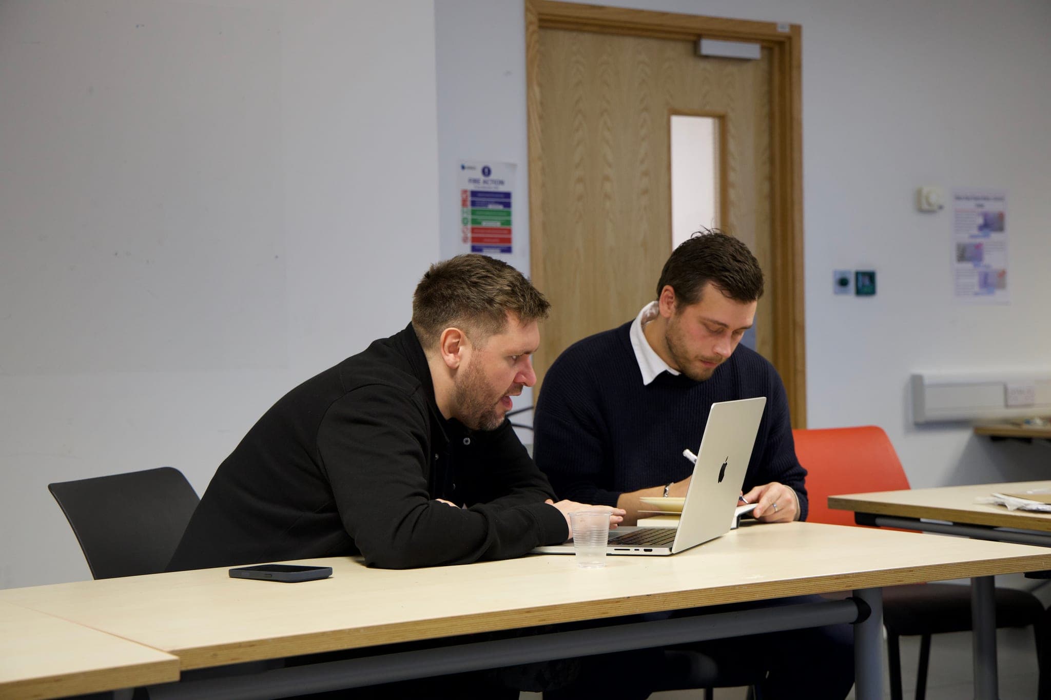 Two people reviewing a laptop together, with one taking notes.