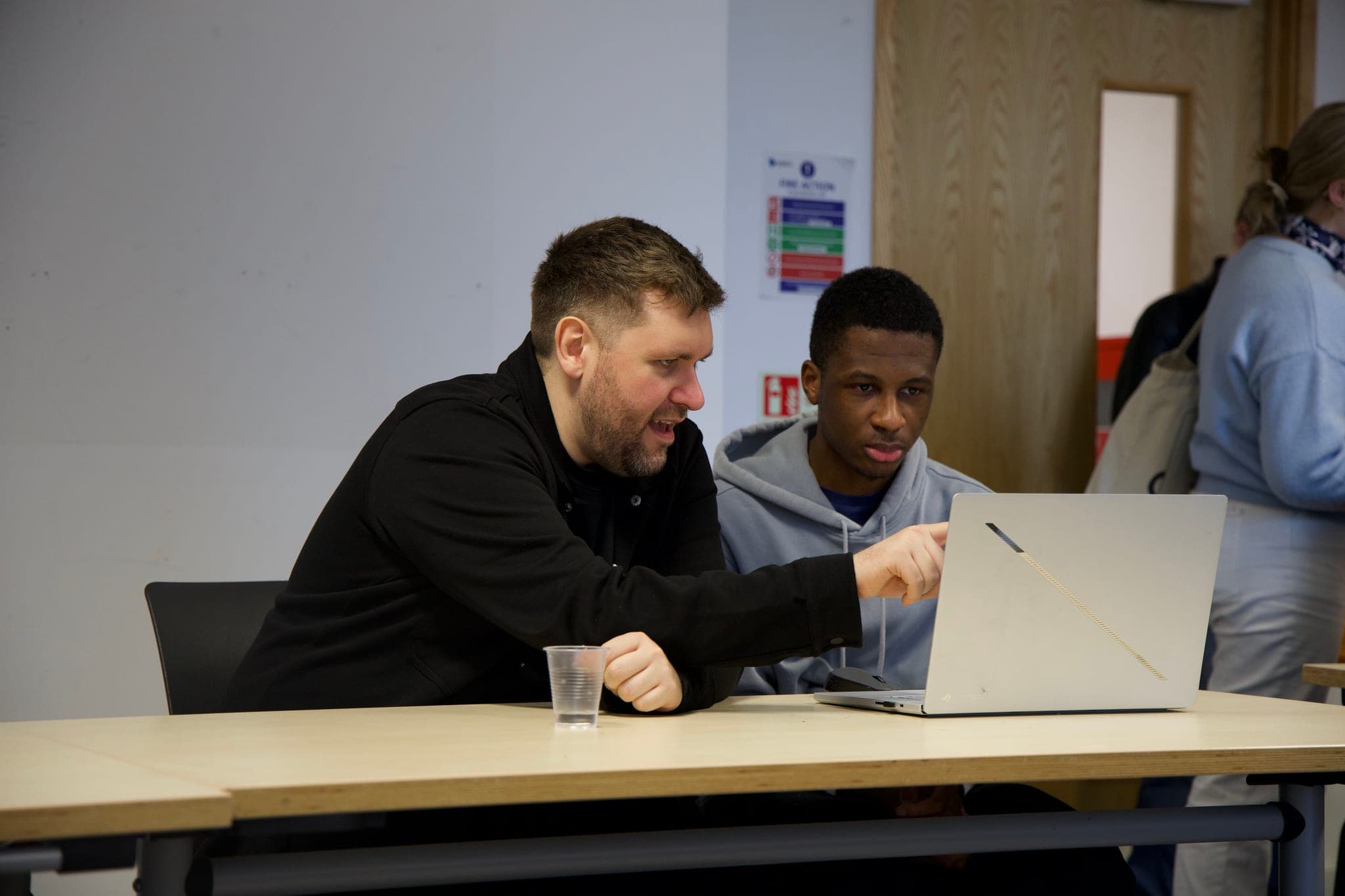 Stephen Drew going through work with a student at a laptop.