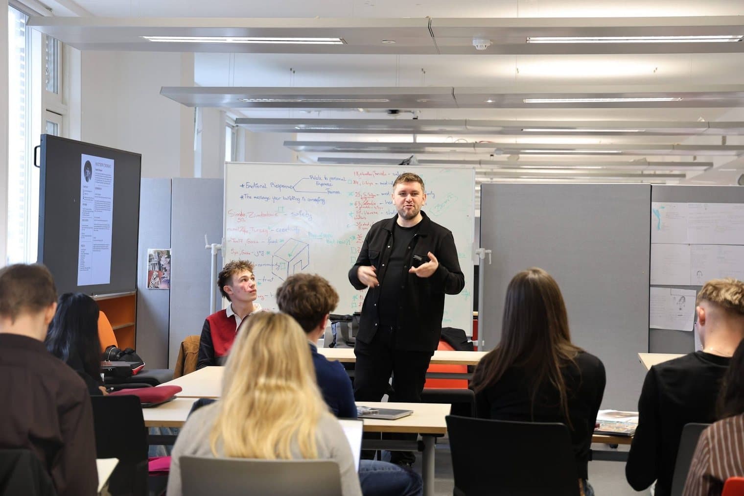 Stephen Drew teaching a studio class, with a whiteboard of notes behind him.