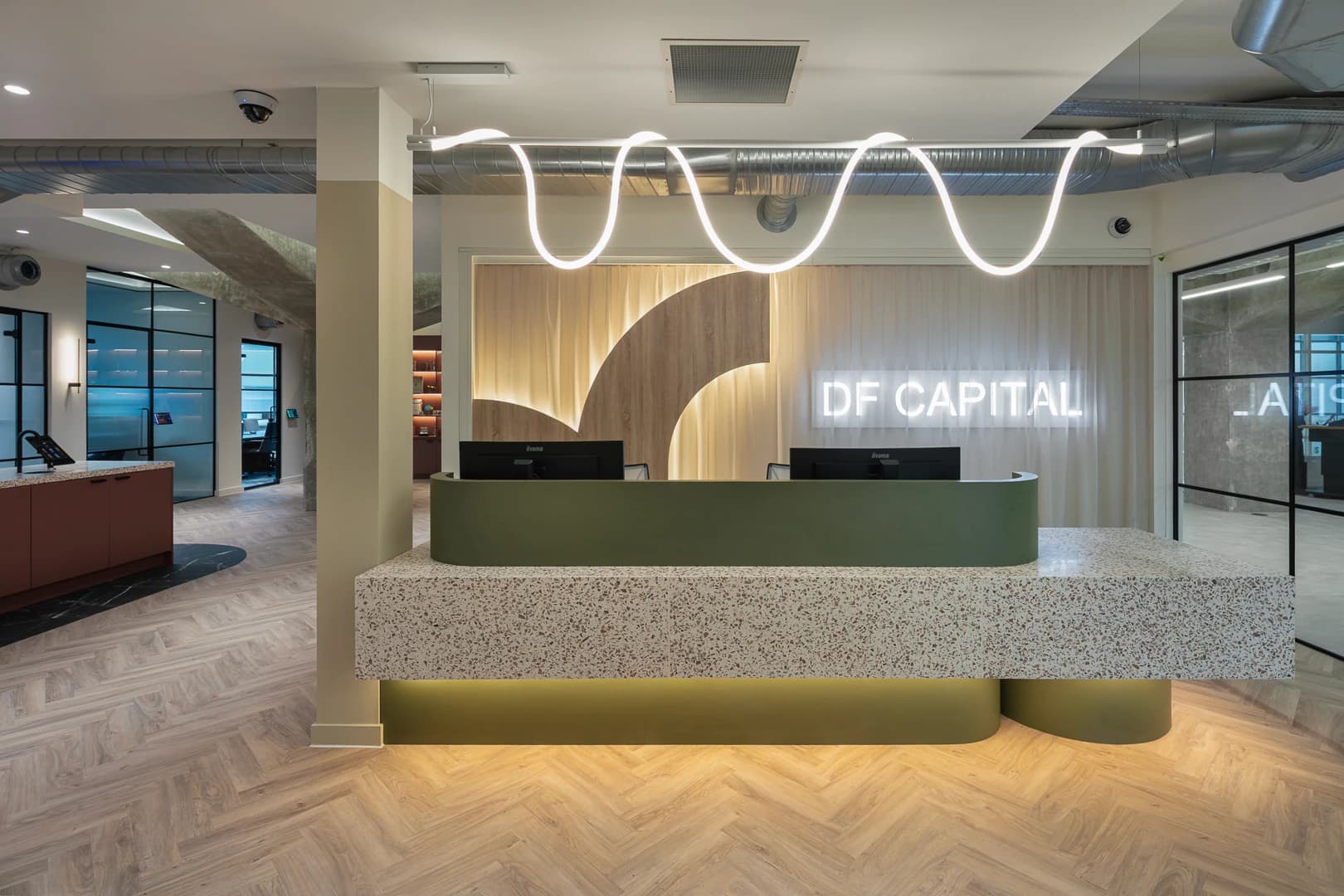 DF Capital reception with a green desk, timber backdrop and looping light