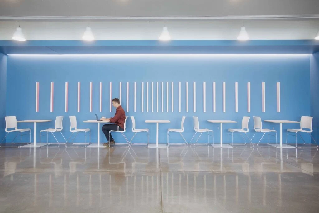 Shared seating and tables beneath a blue-lit wall at Lightbox
